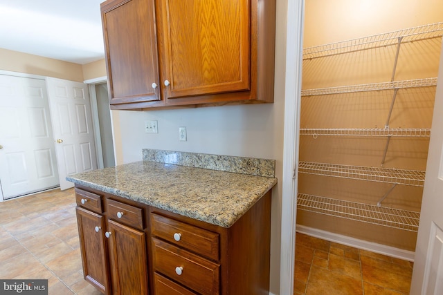 kitchen featuring light stone counters and brown cabinets