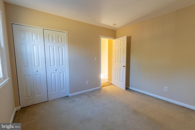 unfurnished bedroom featuring carpet, baseboards, and a closet