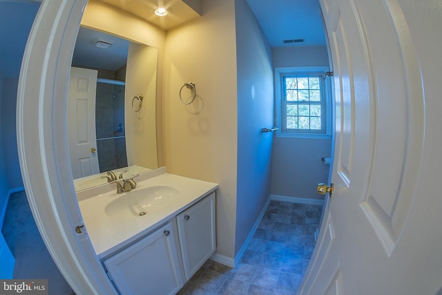 bathroom featuring vanity, baseboards, visible vents, tiled shower, and tile patterned floors