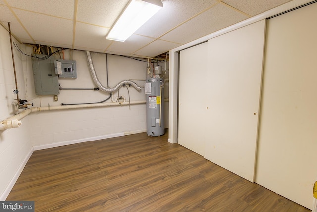 finished basement with electric panel, concrete block wall, wood finished floors, and water heater