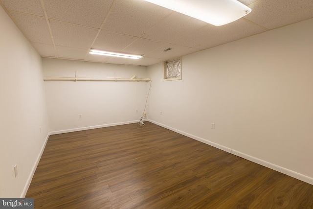 finished below grade area featuring dark wood finished floors, baseboards, and a drop ceiling