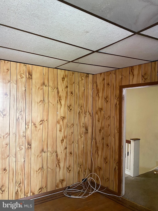 spare room featuring a paneled ceiling, hardwood / wood-style floors, and wooden walls