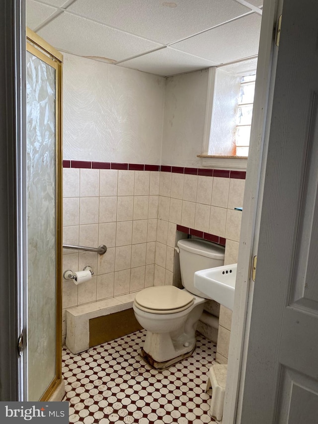 bathroom featuring a paneled ceiling, tile walls, and toilet