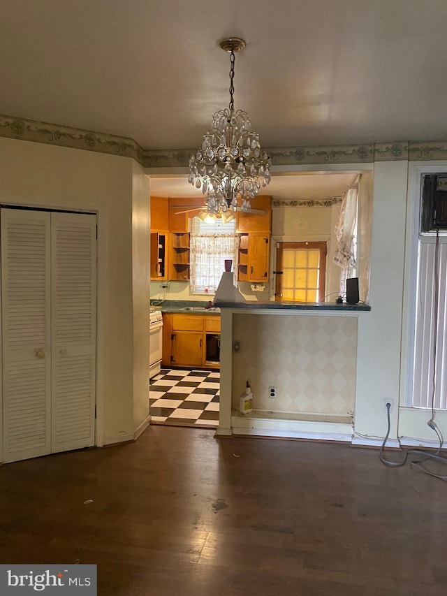 kitchen with an inviting chandelier, white gas range, dark wood-type flooring, and pendant lighting