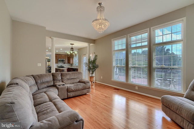 5816 Rockburn Woods Way, Elkridge, MD 21075 - living room featuring an inviting chandelier, decorative columns, and light hardwood / wood-style flooring