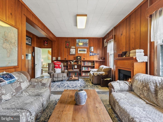 living area with a lit fireplace and wooden walls