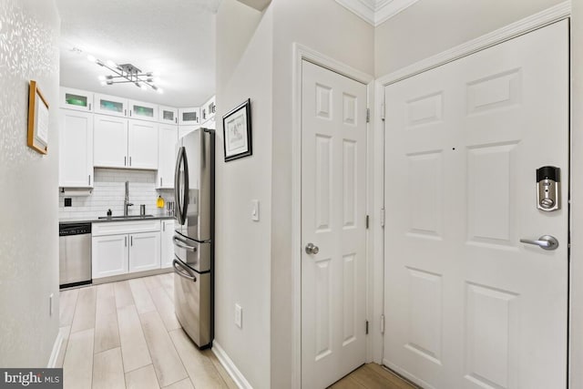 kitchen with glass insert cabinets, white cabinets, stainless steel appliances, and a sink