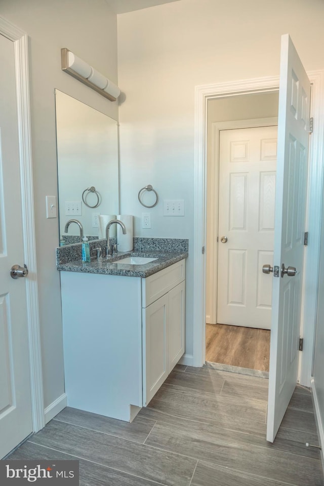 bathroom with wood finished floors, vanity, and baseboards