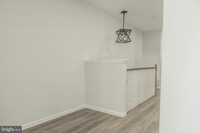 interior space with vaulted ceiling, wood finished floors, an upstairs landing, and baseboards