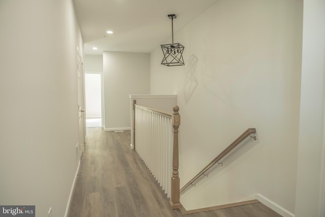 hall featuring recessed lighting, baseboards, an upstairs landing, and wood finished floors