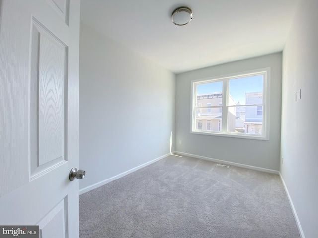 empty room featuring carpet flooring, visible vents, and baseboards