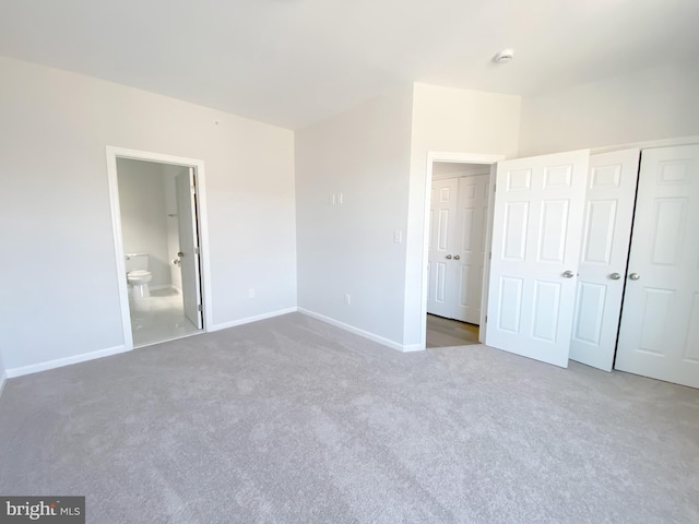 unfurnished bedroom featuring connected bathroom, a closet, baseboards, and carpet flooring