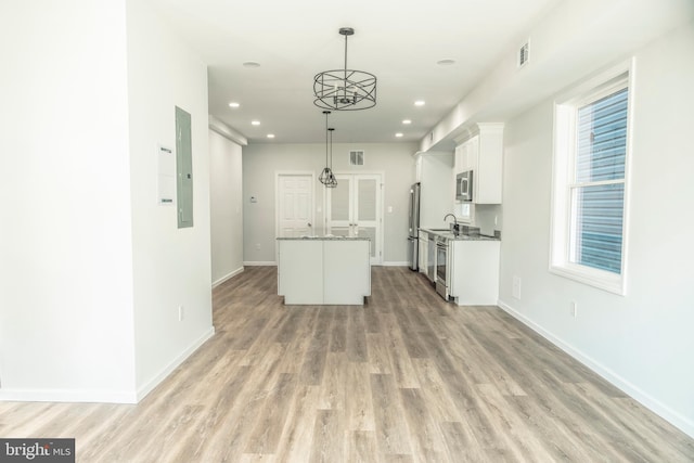 kitchen featuring a center island, stainless steel appliances, visible vents, light wood-style floors, and white cabinets