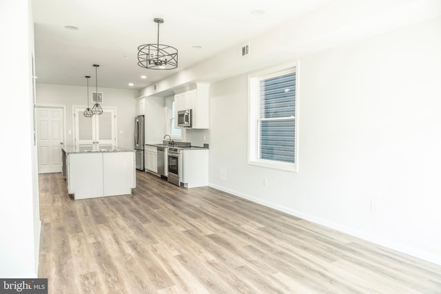 kitchen featuring white cabinets, a kitchen island, stainless steel appliances, light wood-type flooring, and pendant lighting