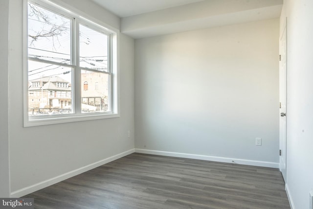 spare room featuring baseboards and dark wood-type flooring