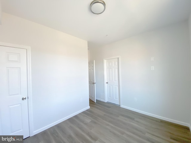 spare room with baseboards and wood finished floors