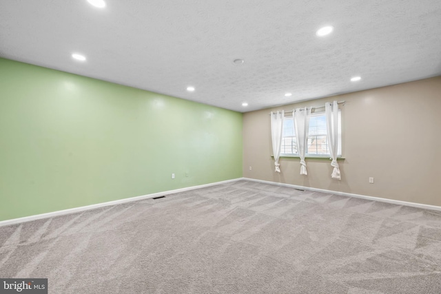 carpeted empty room featuring a textured ceiling, recessed lighting, and baseboards