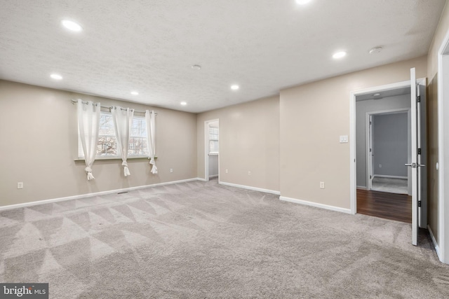 carpeted empty room featuring a textured ceiling, recessed lighting, and baseboards