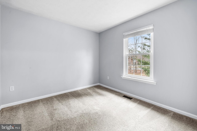 unfurnished room with carpet floors, visible vents, and baseboards