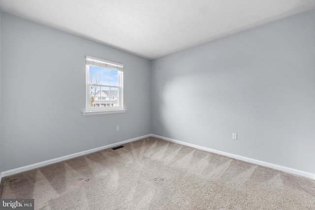 empty room featuring a textured ceiling, carpet flooring, visible vents, and baseboards