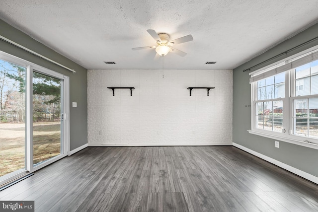 empty room featuring baseboards, a textured ceiling, visible vents, and wood finished floors