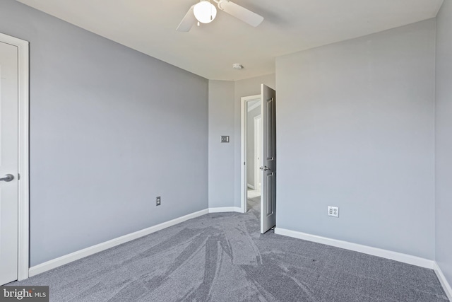 unfurnished bedroom featuring dark colored carpet, a ceiling fan, and baseboards