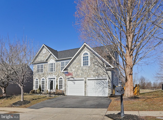 traditional-style home featuring a garage, stone siding, and driveway