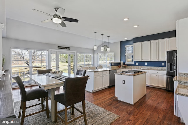 kitchen with a center island, stainless steel appliances, hanging light fixtures, white cabinets, and a peninsula