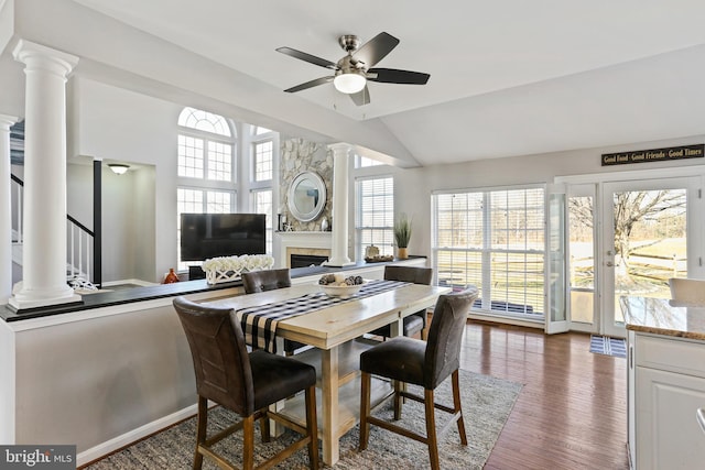 dining space with lofted ceiling, decorative columns, stairs, and dark wood-style flooring