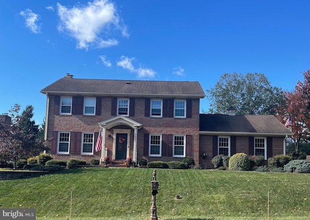 colonial inspired home featuring a front lawn and brick siding