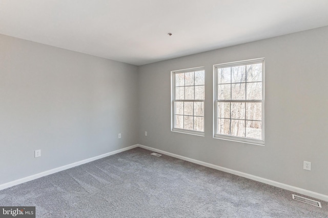 spare room featuring carpet, visible vents, and baseboards