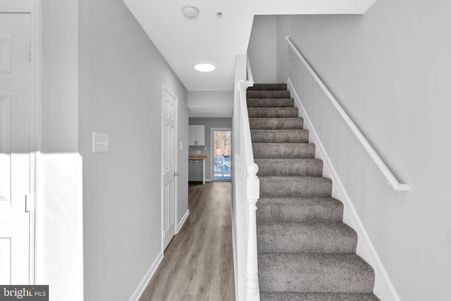 staircase with baseboards and wood finished floors