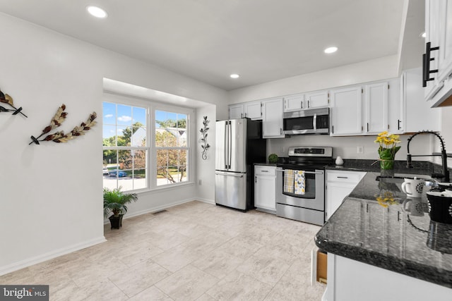 kitchen featuring sink, appliances with stainless steel finishes, white cabinets, and dark stone counters