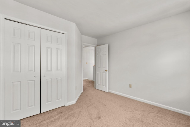 unfurnished bedroom with light carpet and a closet