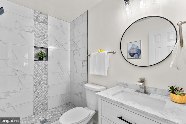 bathroom featuring a tile shower, vanity, and toilet