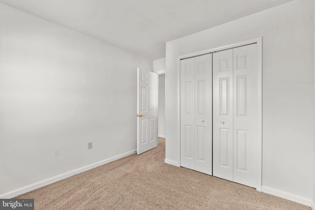 unfurnished bedroom featuring light carpet and a closet