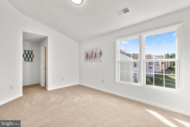 unfurnished room featuring light carpet and vaulted ceiling