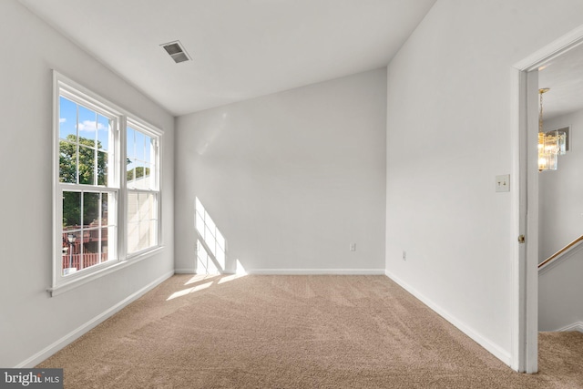 unfurnished room with carpet and an inviting chandelier