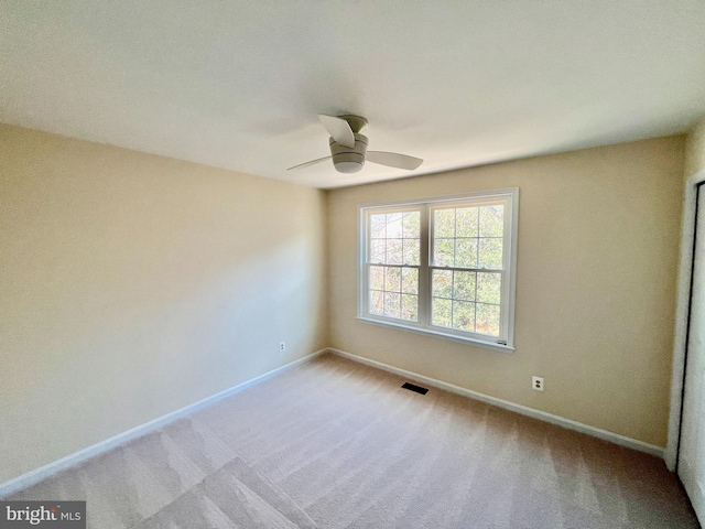 empty room featuring a ceiling fan, baseboards, visible vents, and light carpet