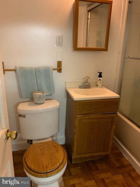 full bathroom featuring shower / bath combination with glass door, vanity, toilet, and parquet flooring