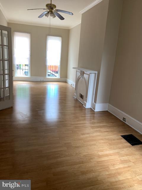 unfurnished living room with ceiling fan, ornamental molding, and light hardwood / wood-style flooring