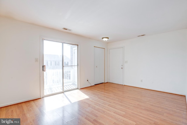 unfurnished room featuring light wood-style flooring, visible vents, and baseboards