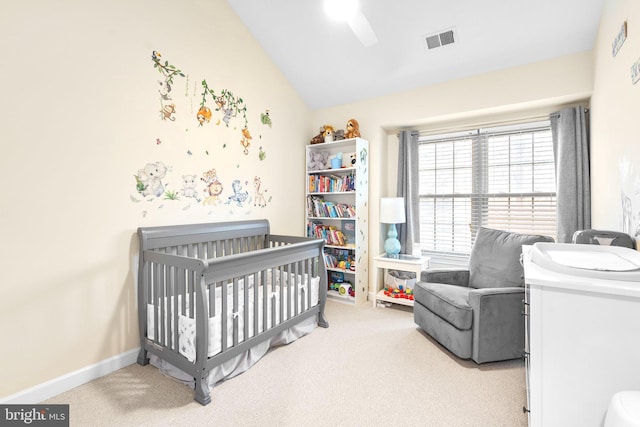 bedroom with vaulted ceiling, visible vents, light carpet, and a crib