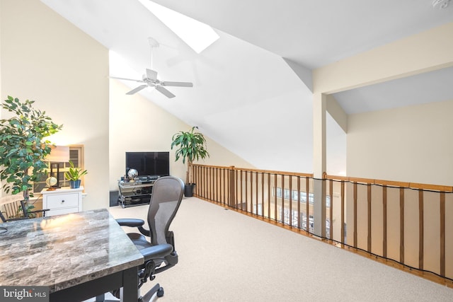 carpeted home office featuring vaulted ceiling with skylight and a ceiling fan