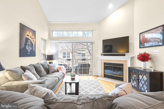 living room with wood finished floors, a high ceiling, and a fireplace with flush hearth