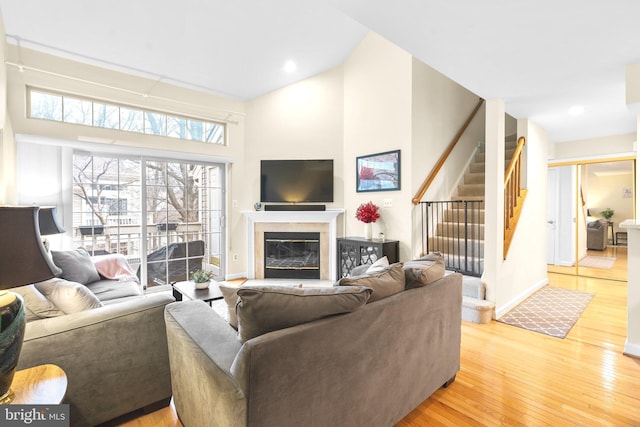 living area featuring wood finished floors, stairs, and a glass covered fireplace