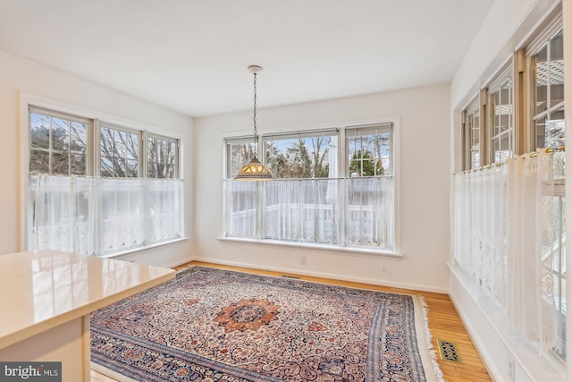 dining area with baseboards, visible vents, and wood finished floors