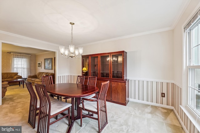 dining room with wainscoting, a healthy amount of sunlight, an inviting chandelier, and light colored carpet
