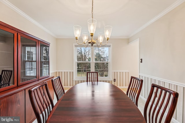 dining room with a wainscoted wall, a chandelier, and ornamental molding