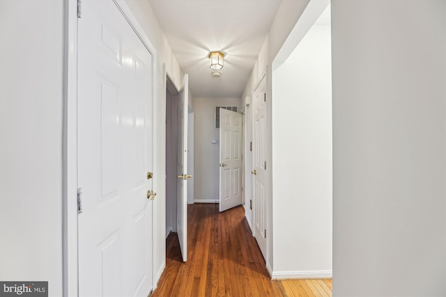 corridor featuring baseboards and wood finished floors